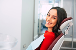 Female patient in red shirt sitting in endodontist&rsquo;s office and smiling