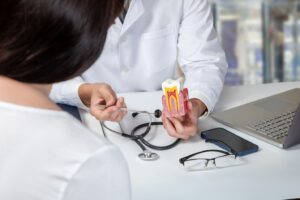 Dentist holding model of infected tooth explaining root canal to patient.